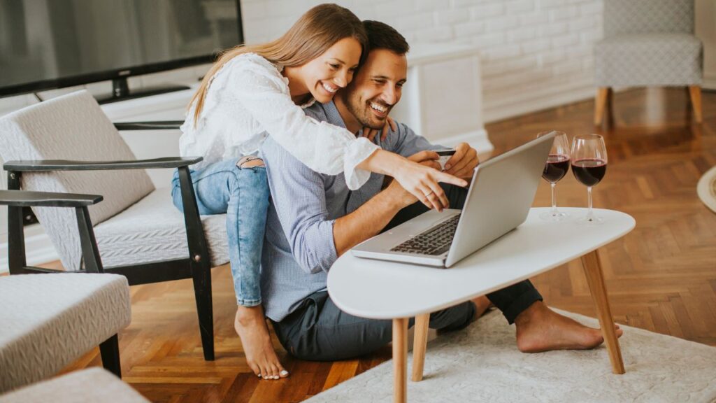 Happy couple using laptop to explore the new Worthington Realty website for homes in Southwest Florida