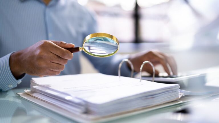 Close-up of person reviewing legal documents with a magnifying glass in Lee County