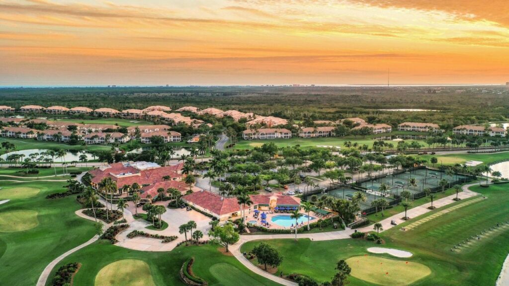 Aerial view of a Southwest Florida HOA community, Lexington Country Club, with golf course, clubhouse, pool, and tennis courts at sunset