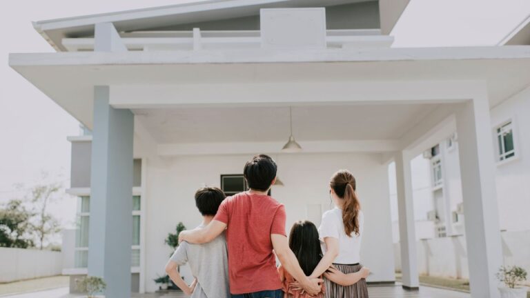 Family standing together looking at their new home — buy and sell a home Fort Myers