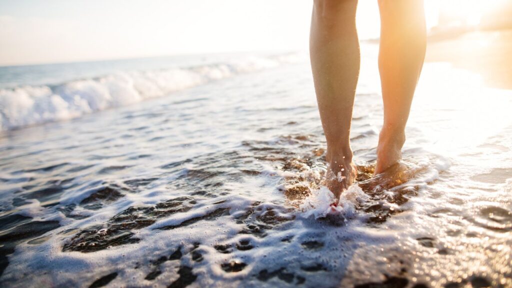 Feet walking along the shoreline at sunset near a luxury Fort Myers Beach vacation rental