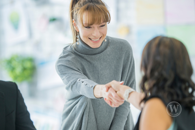 Smiling woman shaking hands with a client – Greater Fort Myers real estate agent building trust with home buyers and sellers.