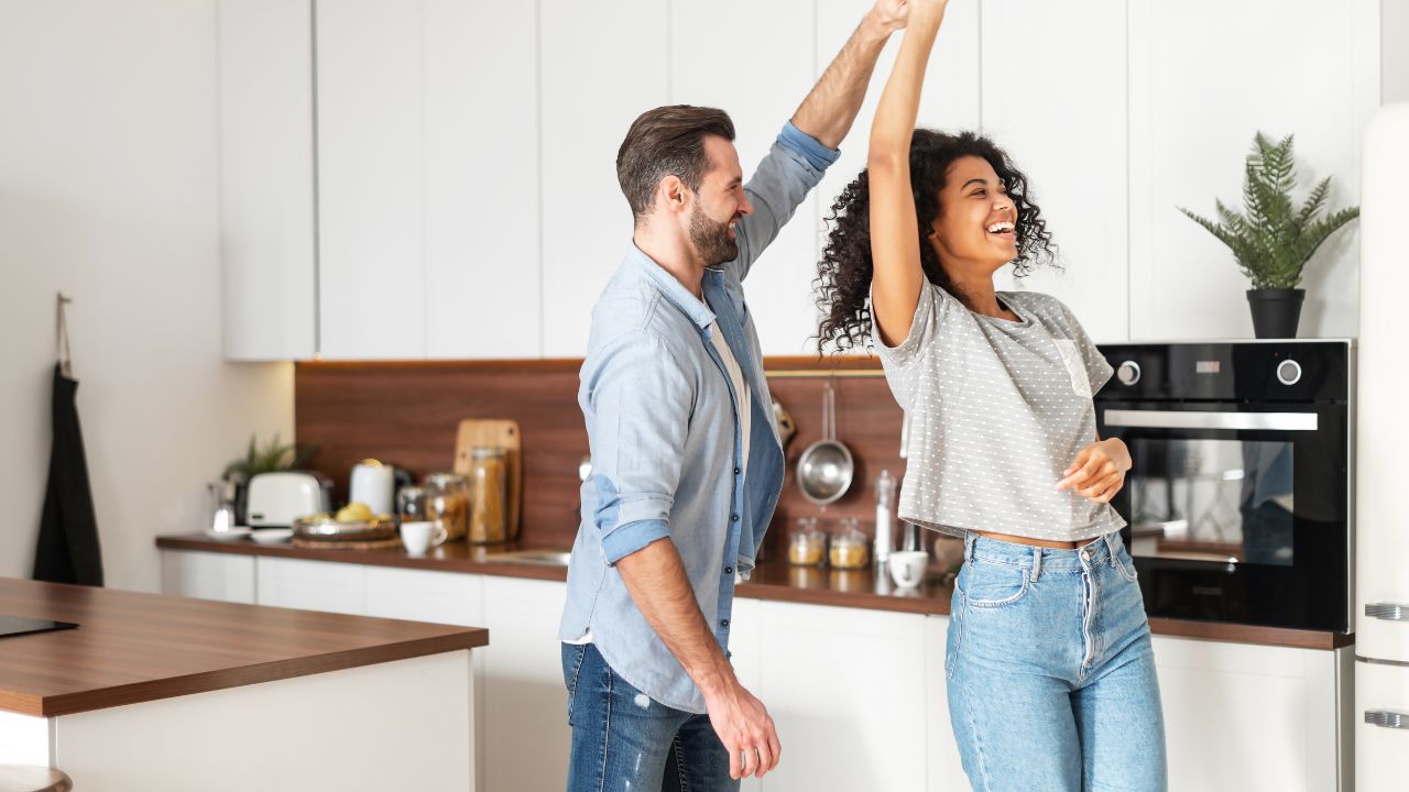 A happy couple dancing in their kitchen, illustrating living comfortably in a home they can afford in Southwest Florida