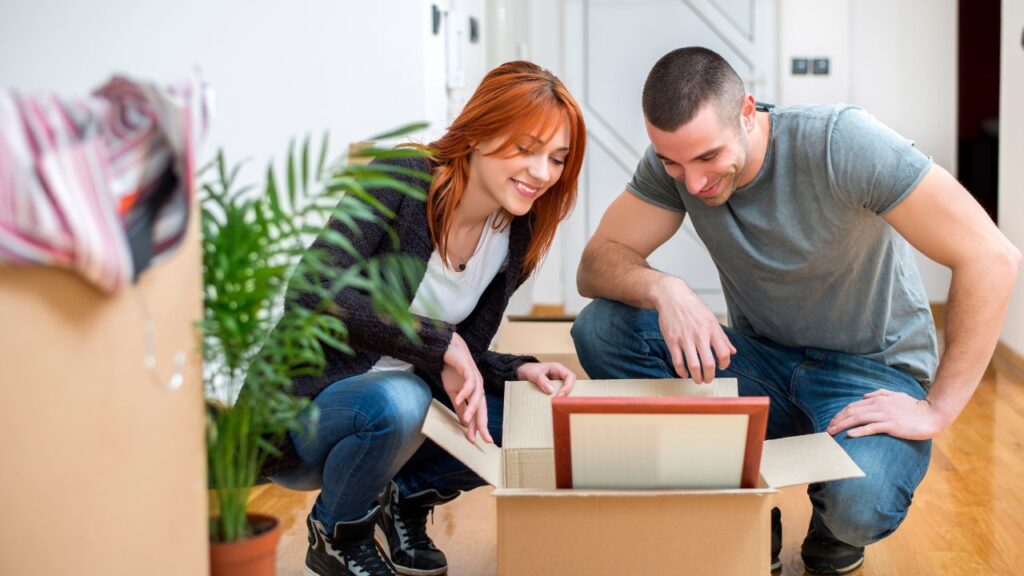 Smiling couple unpacking boxes together on move-in day in their new Fort Myers home