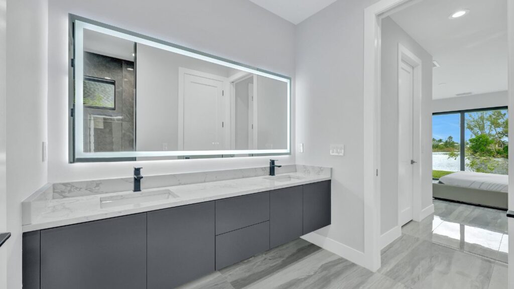 Modern bathroom with double vanity, LED backlit mirror, quartz countertop, matte black fixtures, and large-format tile reflecting Southwest Florida kitchen and bath design