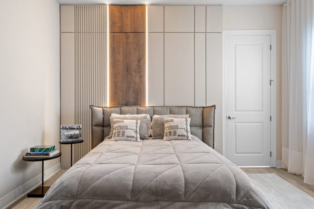 Guest bedroom with warm neutral tones, custom wood-accented headboard, and soft modern lighting in a Southwest Florida home.