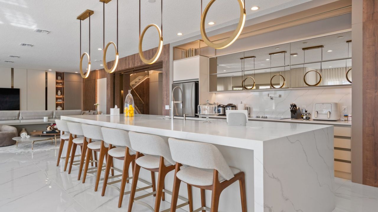 Modern open-concept kitchen with marble countertops and updated lighting, representing current home renovation trends in Southwest Florida