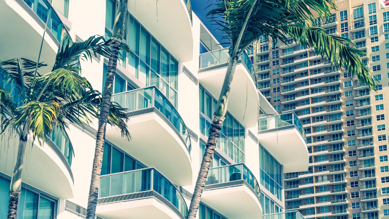 Modern waterfront condominium buildings with palm trees in Southwest Florida, representing the rise in Southwest Florida condos for sale