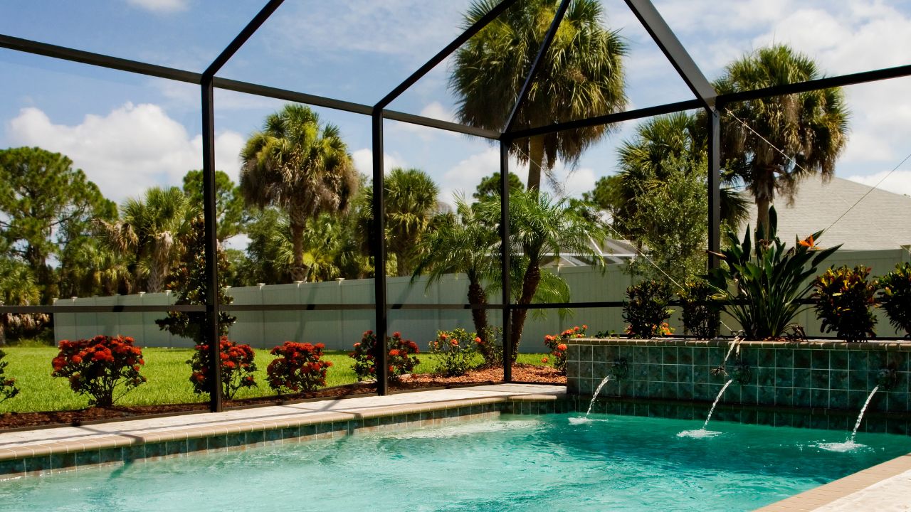 Pool cage hurricane prep in Southwest Florida showing screened enclosure, palm trees, and pool area