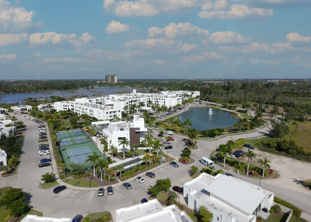 Aerial view of Amavida at Lakes Park in Fort Myers, Florida, featuring white modern residences, tennis courts, lake views, and landscaped walkways.