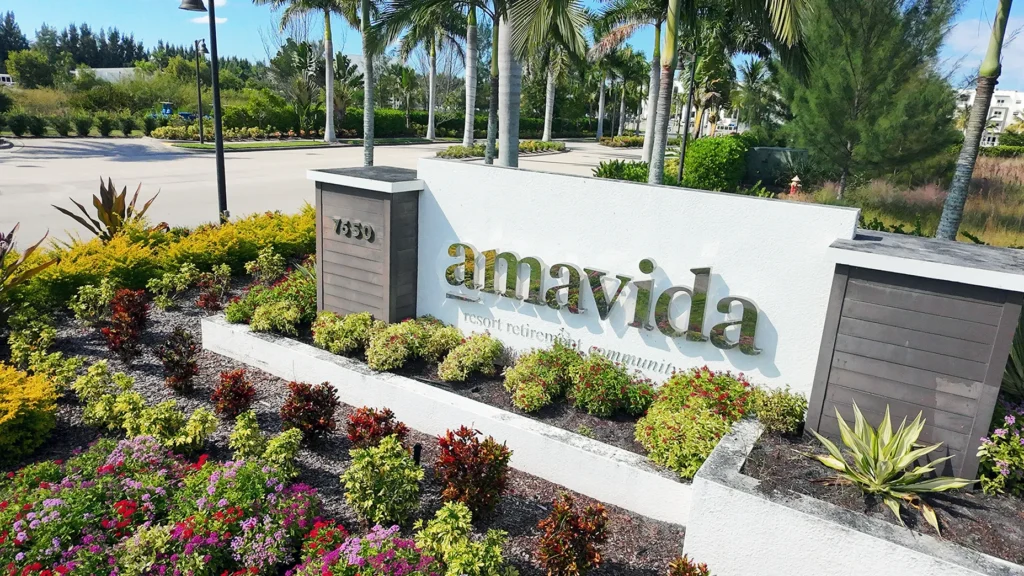 Entrance sign for Amavida at Lakes Park in Fort Myers, surrounded by tropical landscaping and palm trees.