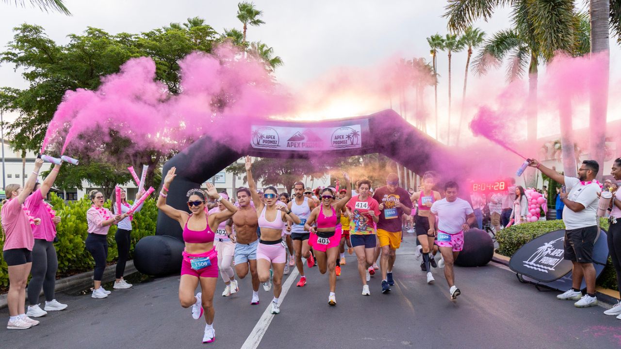 Runners take off through pink smoke at the Partners Pink Run Fort Myers 2025 at Bell Tower Shops, presented by Worthington Realty.