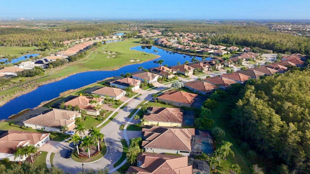 Aerial view of The Plantation community along Treeline Avenue in Fort Myers, showing golf course, lakes, and homes with tile roofs.
