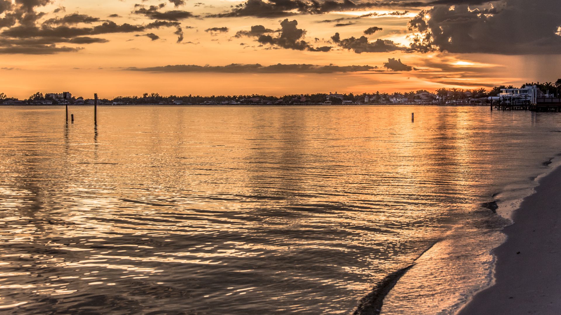 Sunset view over the Caloosahatchee River from Cape Coral Yacht Club Beach, showing calm water, shoreline, and waterfront homes that reflect the neighborhood’s coastal lifestyle.