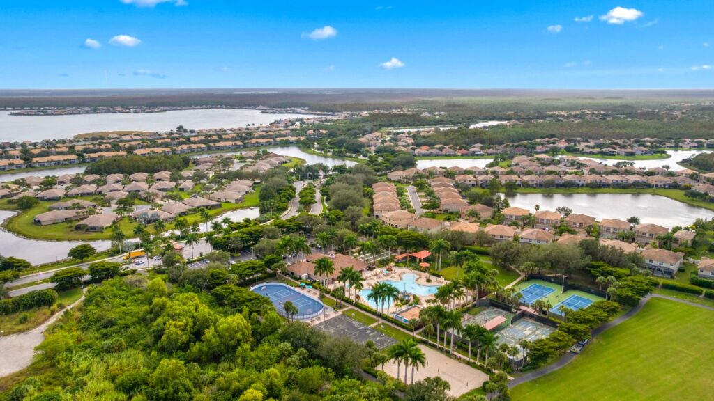 Aerial view of Bella Terra in Estero, Florida showing lakes, single-family homes, clubhouse, and tennis courts.