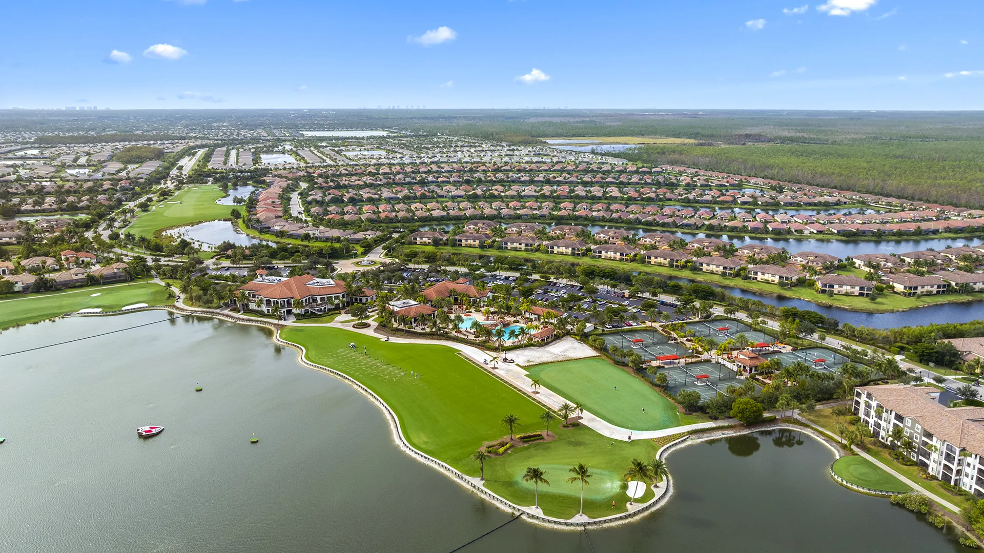 Aerial view of Bonita National Golf & Country Club in Bonita Springs, FL, featuring the 18-hole championship golf course, lakes, clubhouse, resort-style pool, tennis courts, and homes for sale