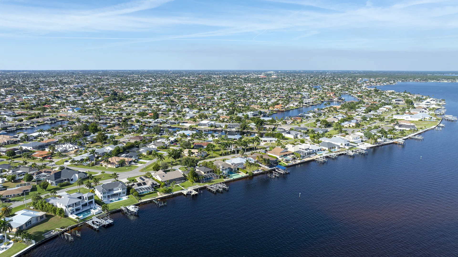 Aerial view of waterfront homes in Cape Coral, FL, featuring direct Gulf-access canals, private boat docks, riverfront properties along the Caloosahatchee, pools, and homes for sale with boating access.
