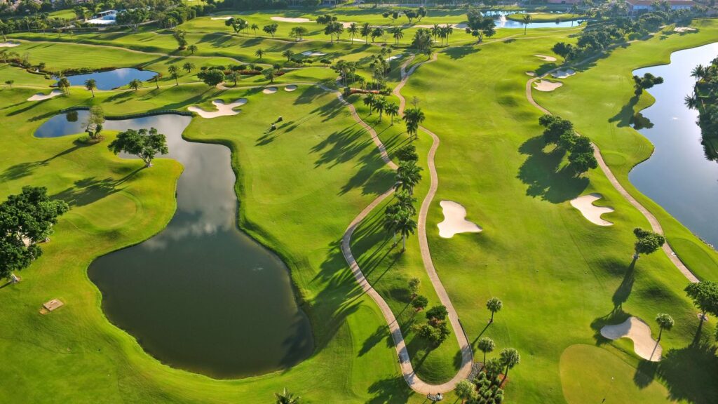 Aerial view of an Estero, Florida golf course with lakes, fairways, and palm-lined cart paths at sunrise. Featured image for the Estero real estate market update.