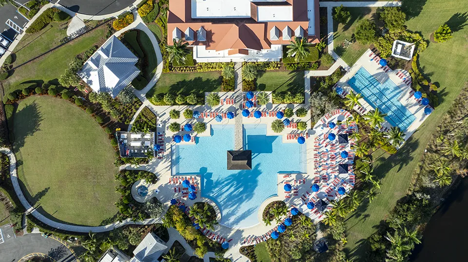 Aerial view of the clubhouse, resort-style pool, and tennis courts at Isles of Collier Preserve, a gated community with homes for sale in Naples, FL