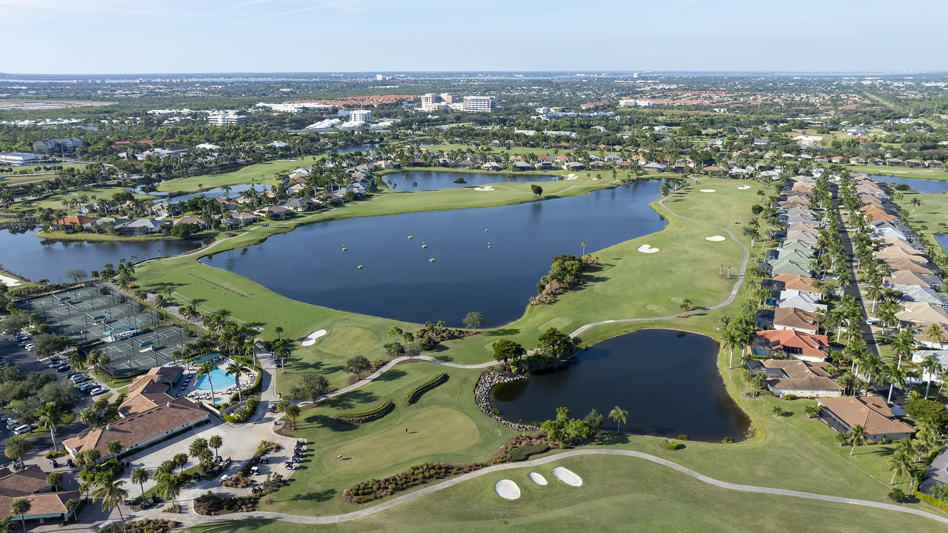 Aerial view of Lexington Country Club in Fort Myers, FL, showing the bundled golf course, lakes, resort-style pool, tennis courts, clubhouse, and surrounding homes for sale.