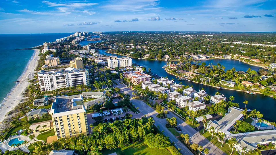 Aerial view of luxury high-rise condos along the Gulf of Mexico beach in Naples, FL, highlighting pristine white-sand shores and turquoise waters