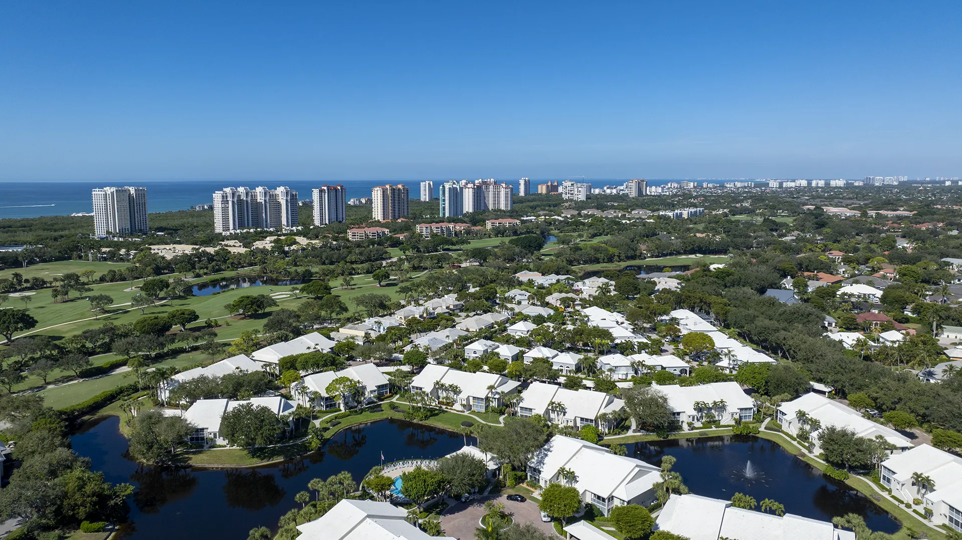 Aerial view of Pelican Bay in North Naples, FL, a luxury beachfront community with homes for sale featuring Gulf views, high-rise condos, golf courses, and private beach clubs