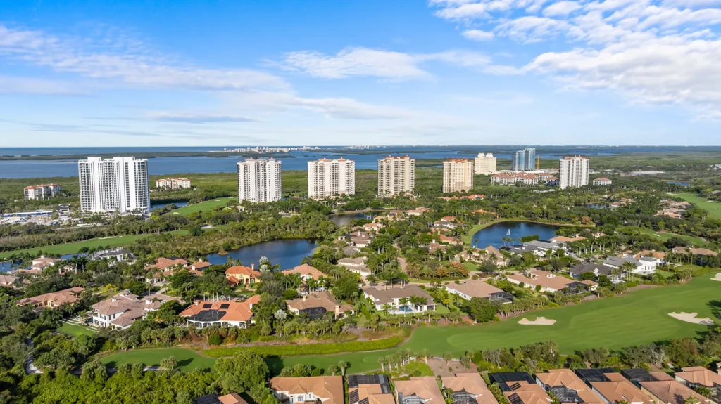Aerial view of Pelican Landing in Bonita Springs, FL, showcasing the gated master-planned community with lakes, preserves, championship golf course, and luxury homes for sale near the private Gulf-front beach club.