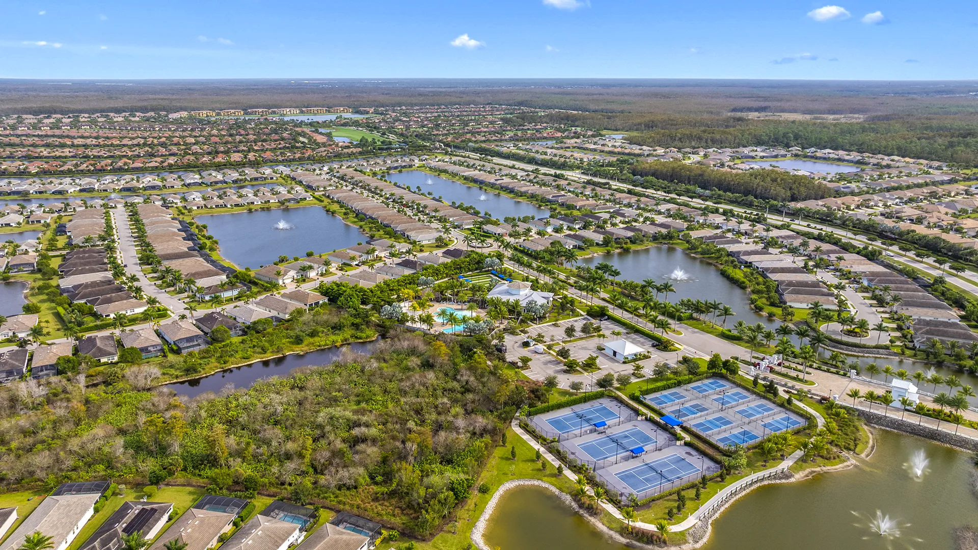 Aerial view of Seasons at Bonita, a gated all-ages community with single-family homes for sale arranged around lakes and preserves in Bonita Springs, FL