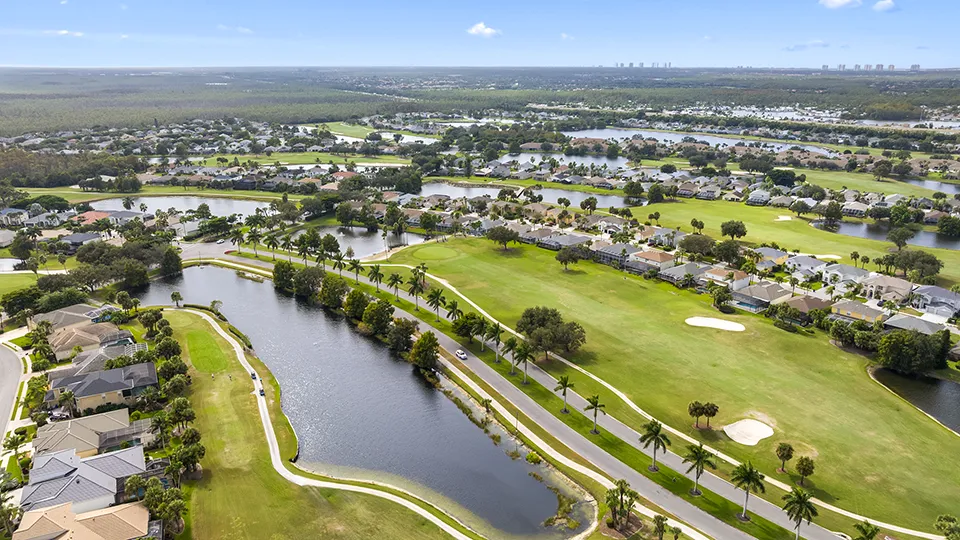 Aerial view of Stoneybrook in Estero, FL, showcasing the public 18-hole golf course, lakes, tennis courts, resort-style pool area, clubhouse, and gated community homes for sale.