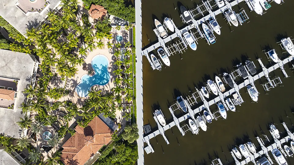 Aerial view of Tarpon Point amenities in Cape Coral, FL, featuring the resort-style swimming pool, clubhouse, full-service marina with boat slips, and direct Gulf access for homes for sale.