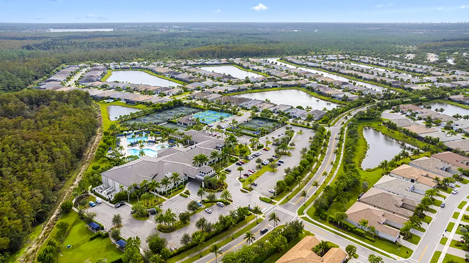 Aerial view of the clubhouse, resort-style pool, lap pool, resistance pool, tennis, and pickleball courts at Valencia Bonita, a 55+ community with homes for sale in Bonita Springs, FL