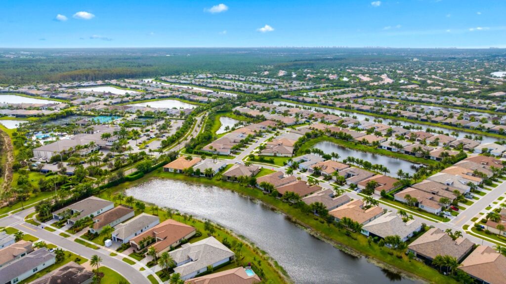 Aerial view of Valencia Bonita in Bonita Springs featuring lakefront homes, clubhouse, pools, and planned streets.