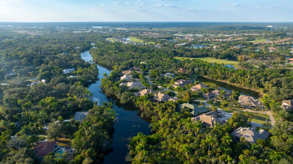 Aerial view of Verandah in Fort Myers showing wooded areas, riverfront homes, and surrounding golf features.