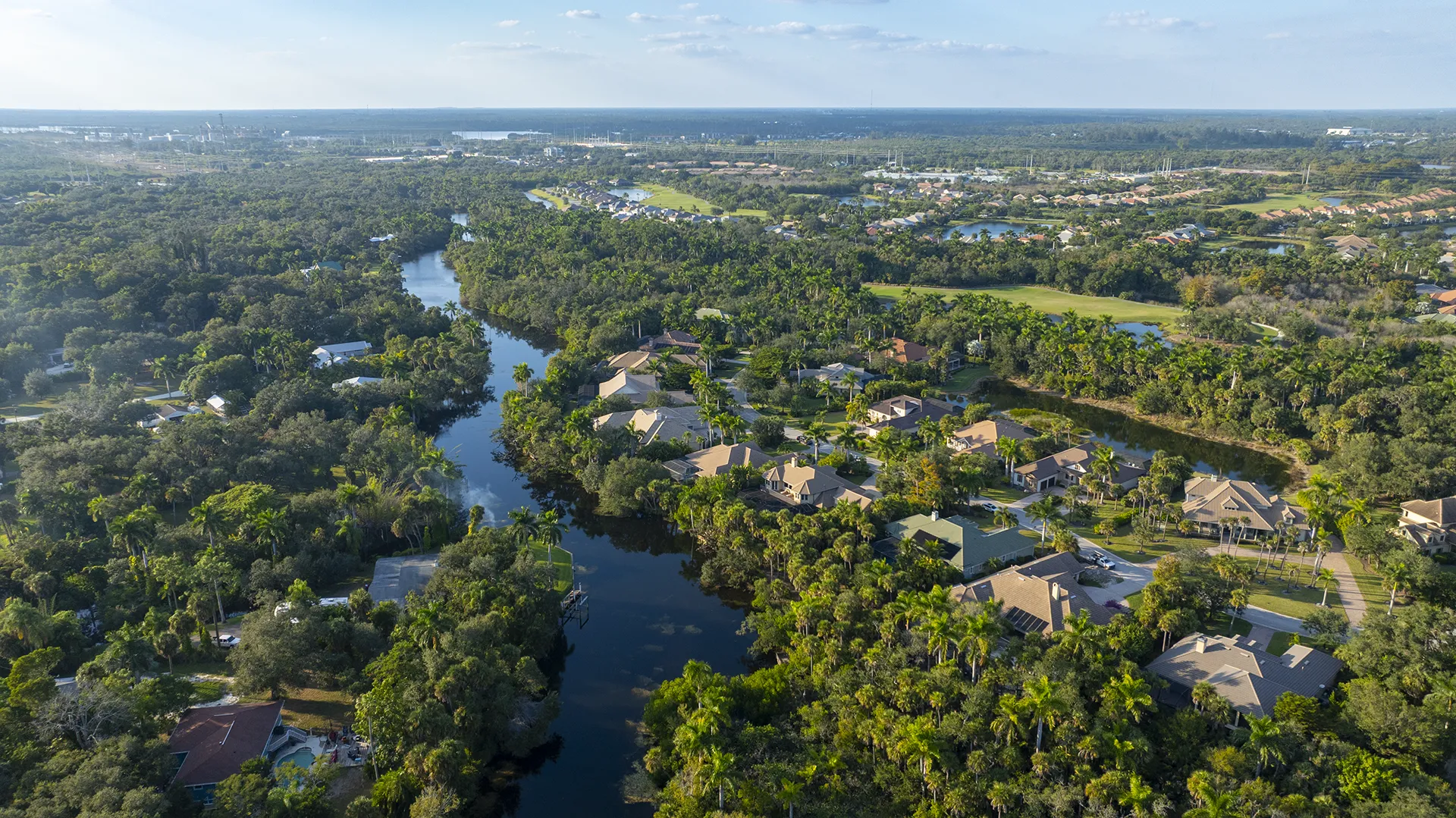 Aerial view of Verandah in Fort Myers, FL, showcasing the Orange River frontage, two championship golf courses, nature trails, kayak access, and homes for sale along the water.