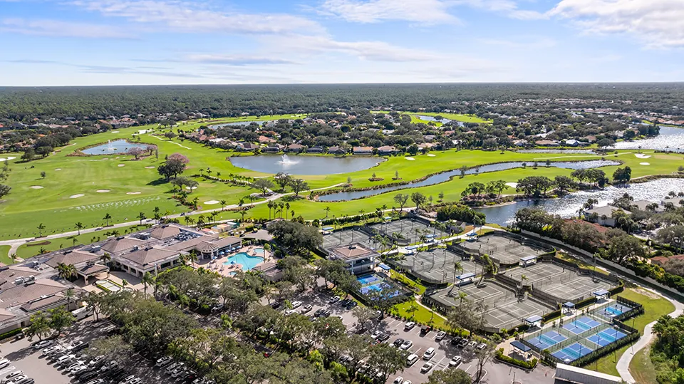 Aerial view of condos, lakes, and golf course at The Vineyards, a gated community with homes for sale featuring water views and mature landscaping in North Naples, FL