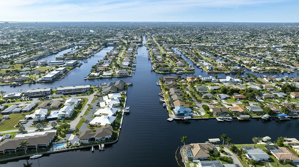 Aerial view of Cape Coral waterfront homes along Gulf-access canals, featuring private boat docks, canal-front properties, pools, and direct boating access to the Gulf of Mexico.