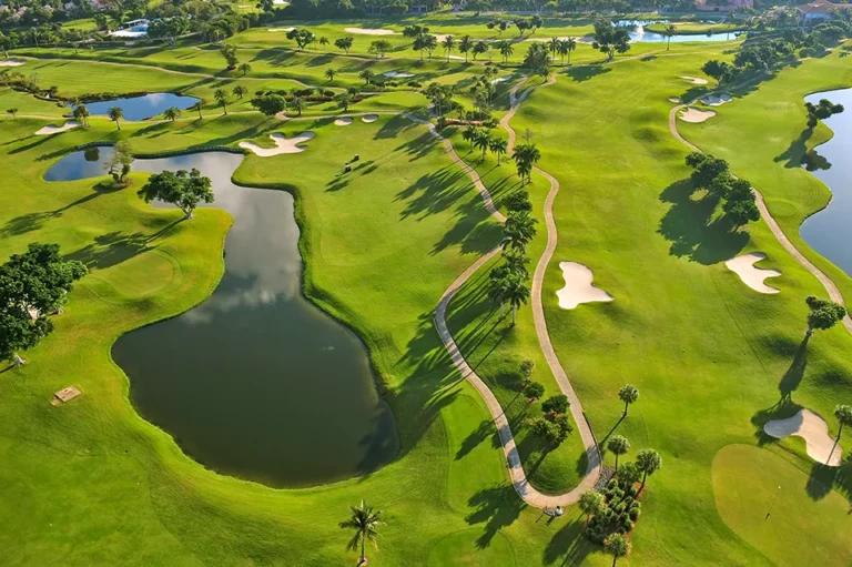 Aerial view of a lush golf course with lakes, sand bunkers, and winding cart paths
