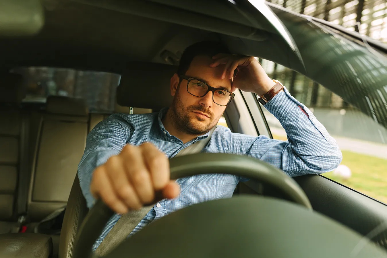 Real estate agent sitting alone in car between showings, looking exhausted and questioning whether the career is worth it