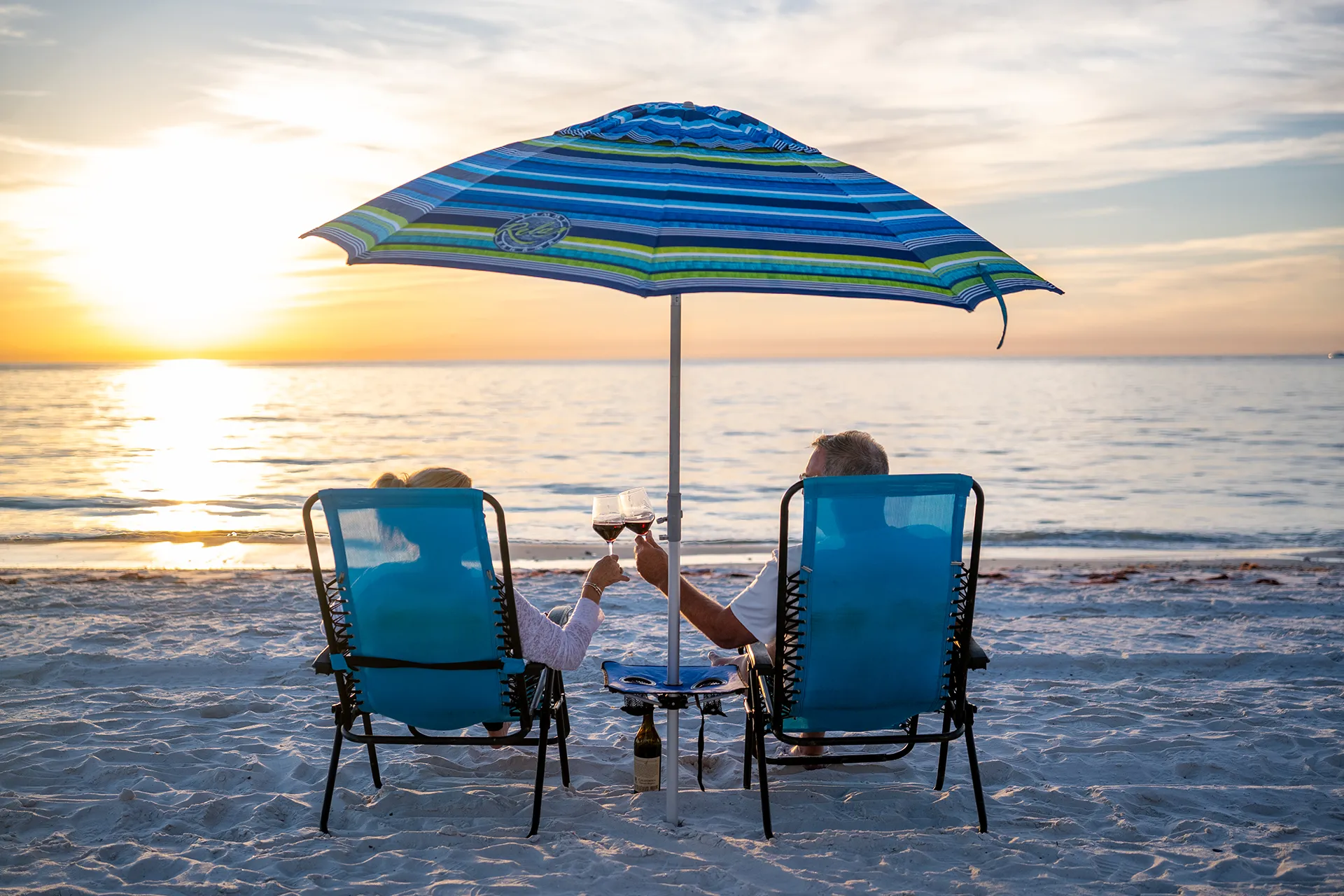 Couple watching a Gulf of Mexico sunset from beach chairs on a Southwest Florida beach