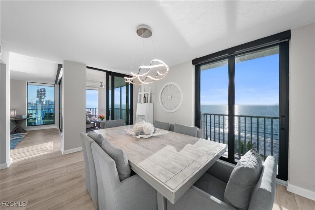 Dining room with direct Gulf views and modern chandelier in top-floor Naples condo at Bayshores Vanderbilt Beach