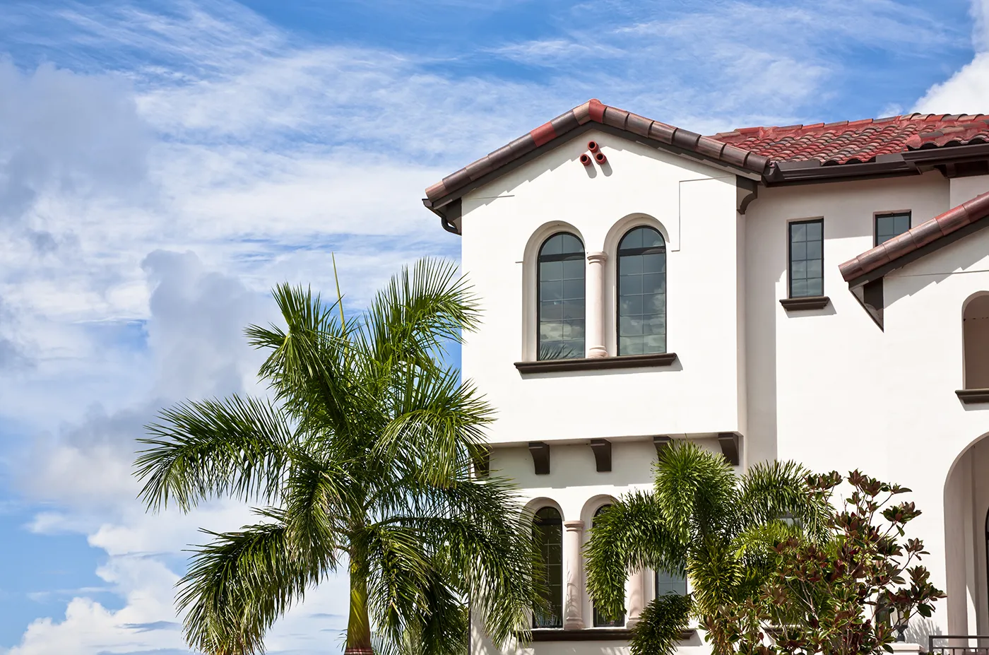 Mediterranean-style home with red tile roof and palm trees in Southwest Florida