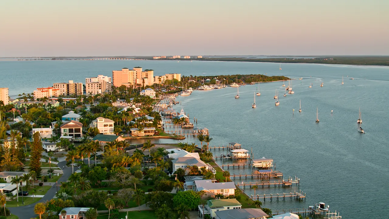Aerial view of Fort Myers Beach waterfront condos, marina, and bay at sunset