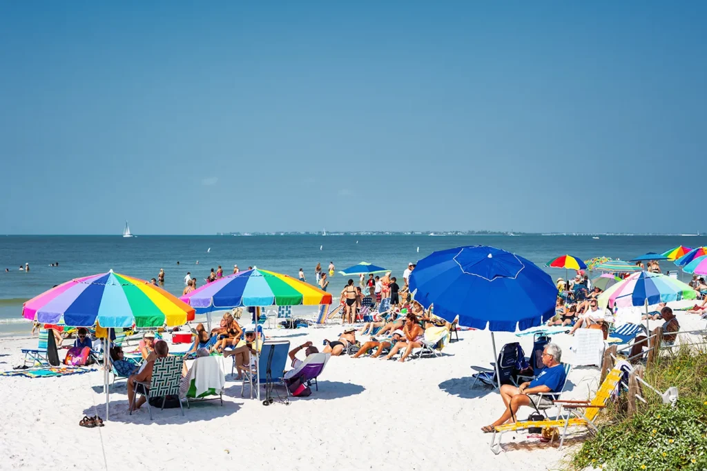Southwest Florida summer beach conditions in 2026 with families enjoying clear Gulf water and colorful umbrellas on a sunny beach