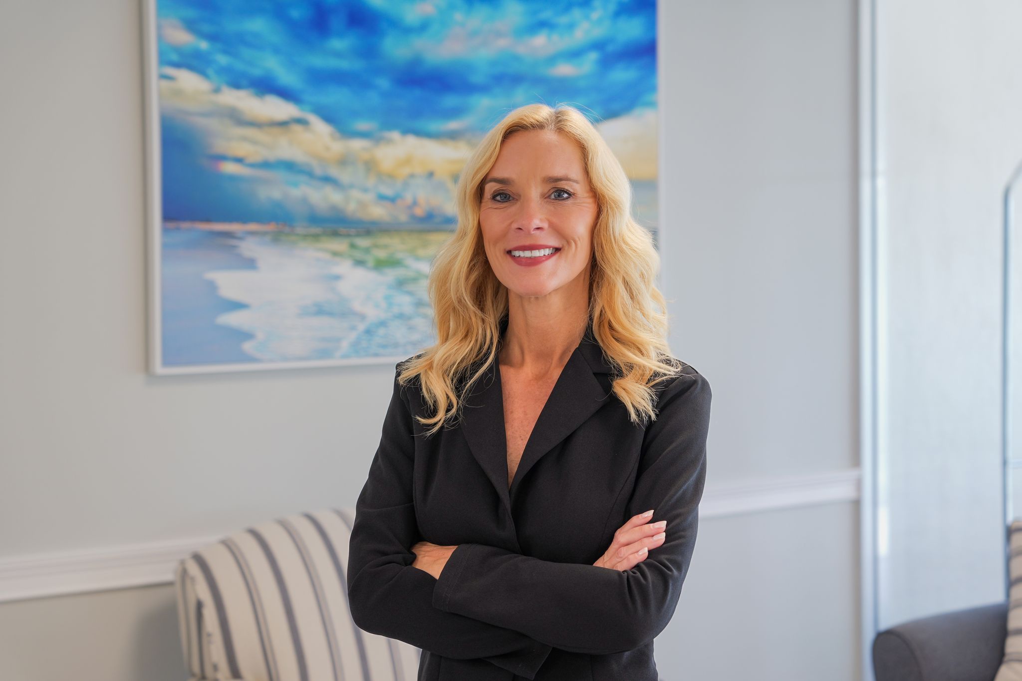 Amy Fossett, North Naples Realtor with Worthington Realty, standing with her arms crossed in a bright coastal interior.