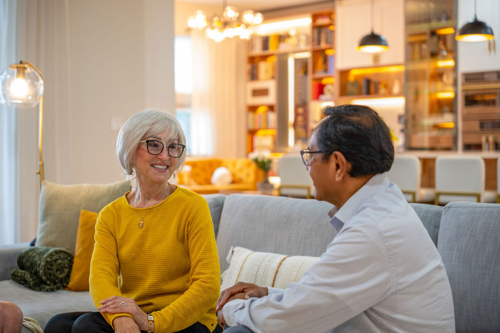 Attractive couple sitting on a couch having a conversation in a bright living room