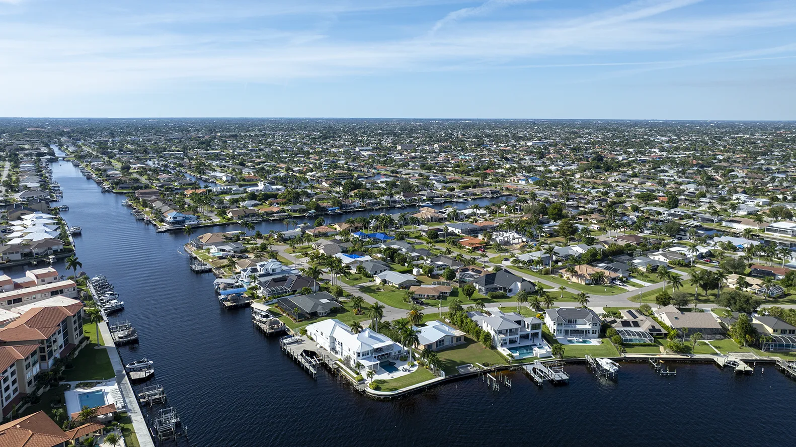 Aerial view of a waterfront neighborhood with canals, docks, and single-family homes under a clear sky