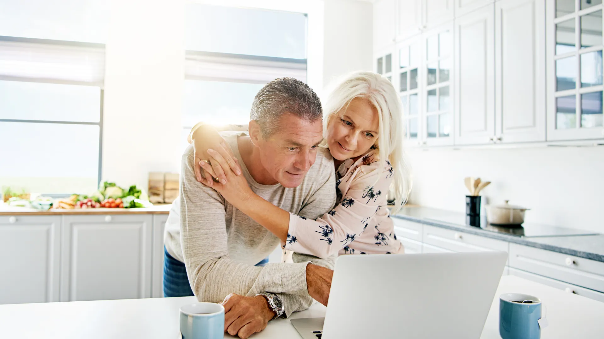 Mature couple reviewing the monthly cost of owning a home in Southwest Florida on a laptop in a bright kitchen