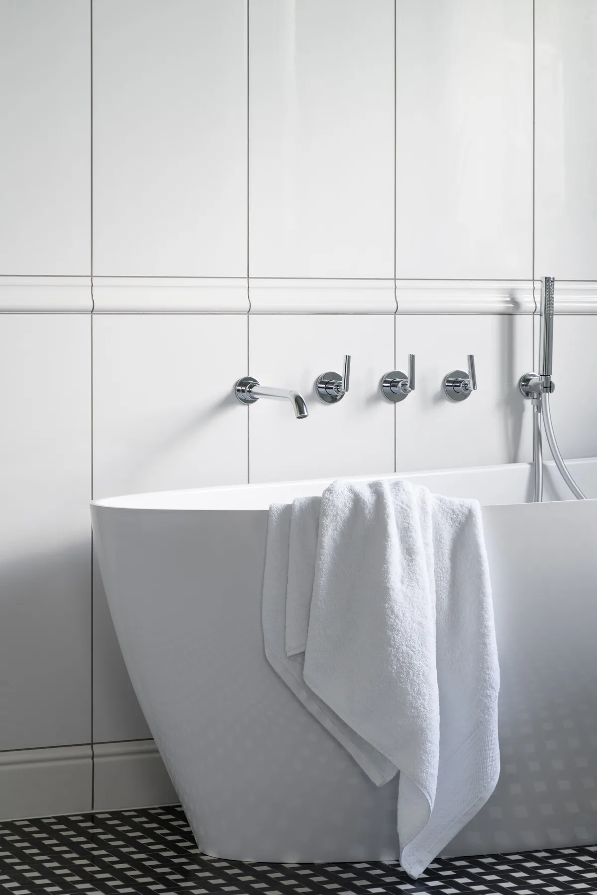 Bright bathroom with a freestanding soaking tub and a crisp white towel