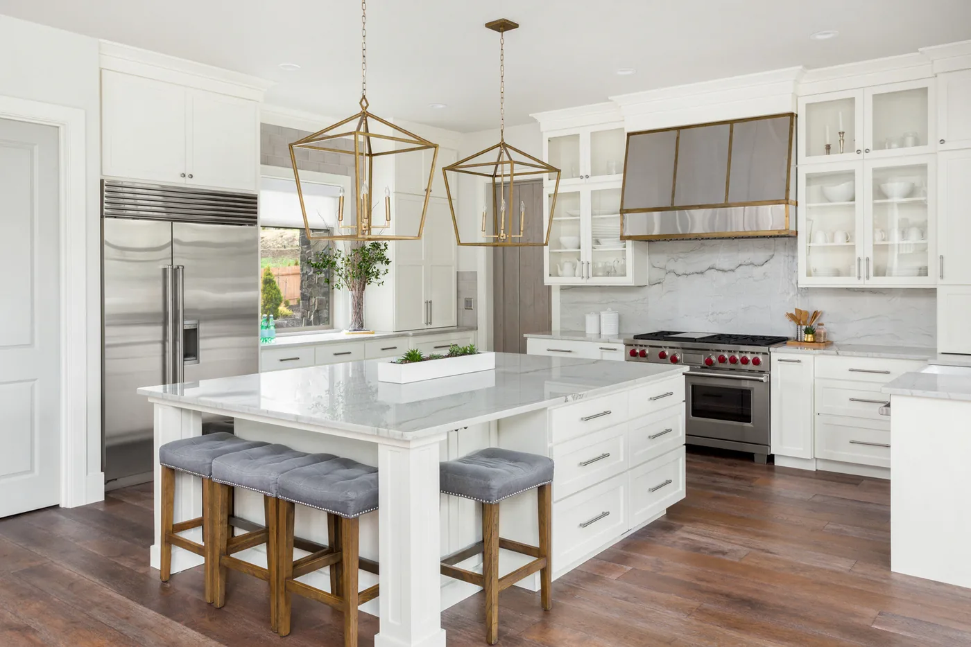 Bright white kitchen with a marble island, counter stools, and pendant lighting