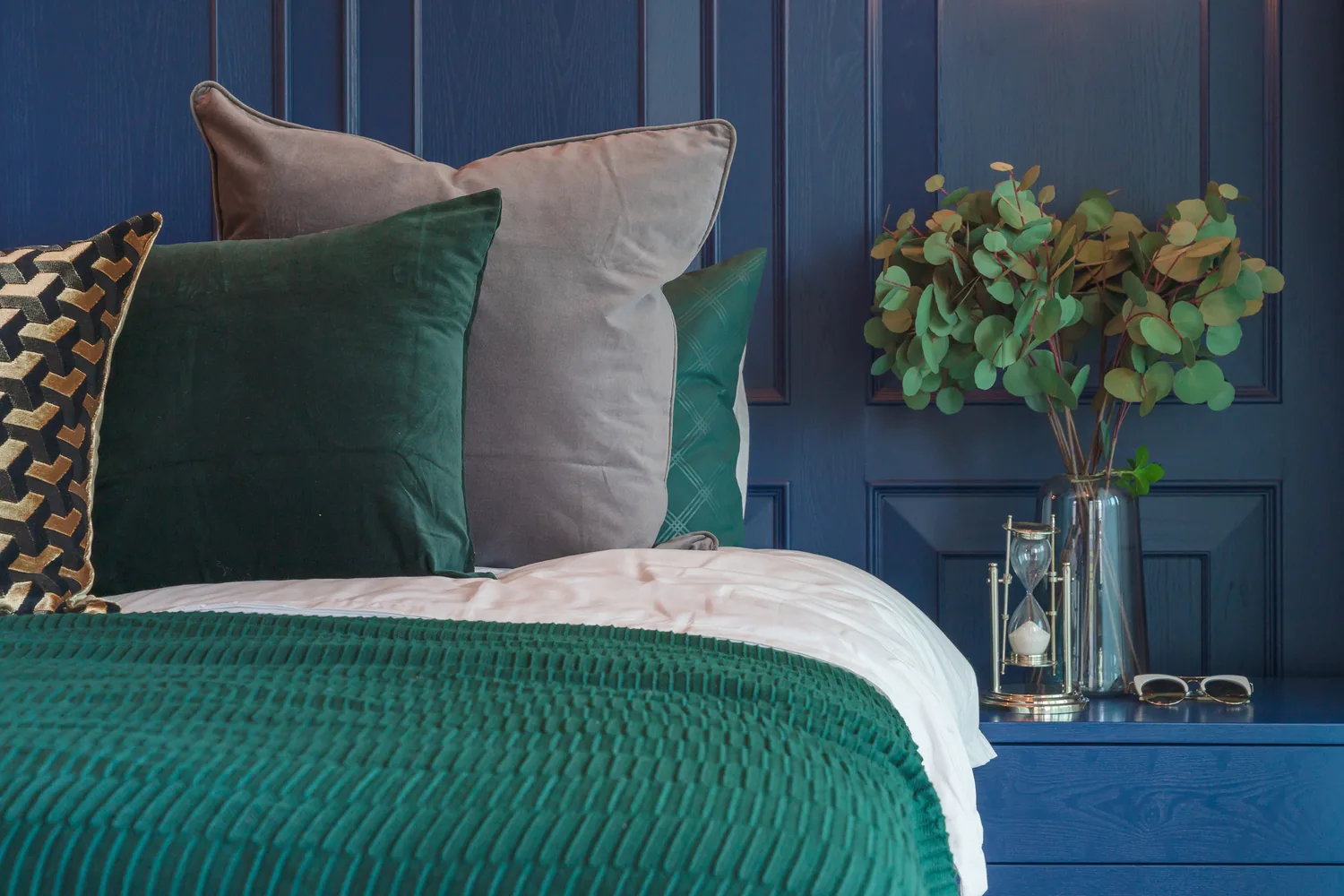 Serene bedroom with a navy paneled wall and layered bedding